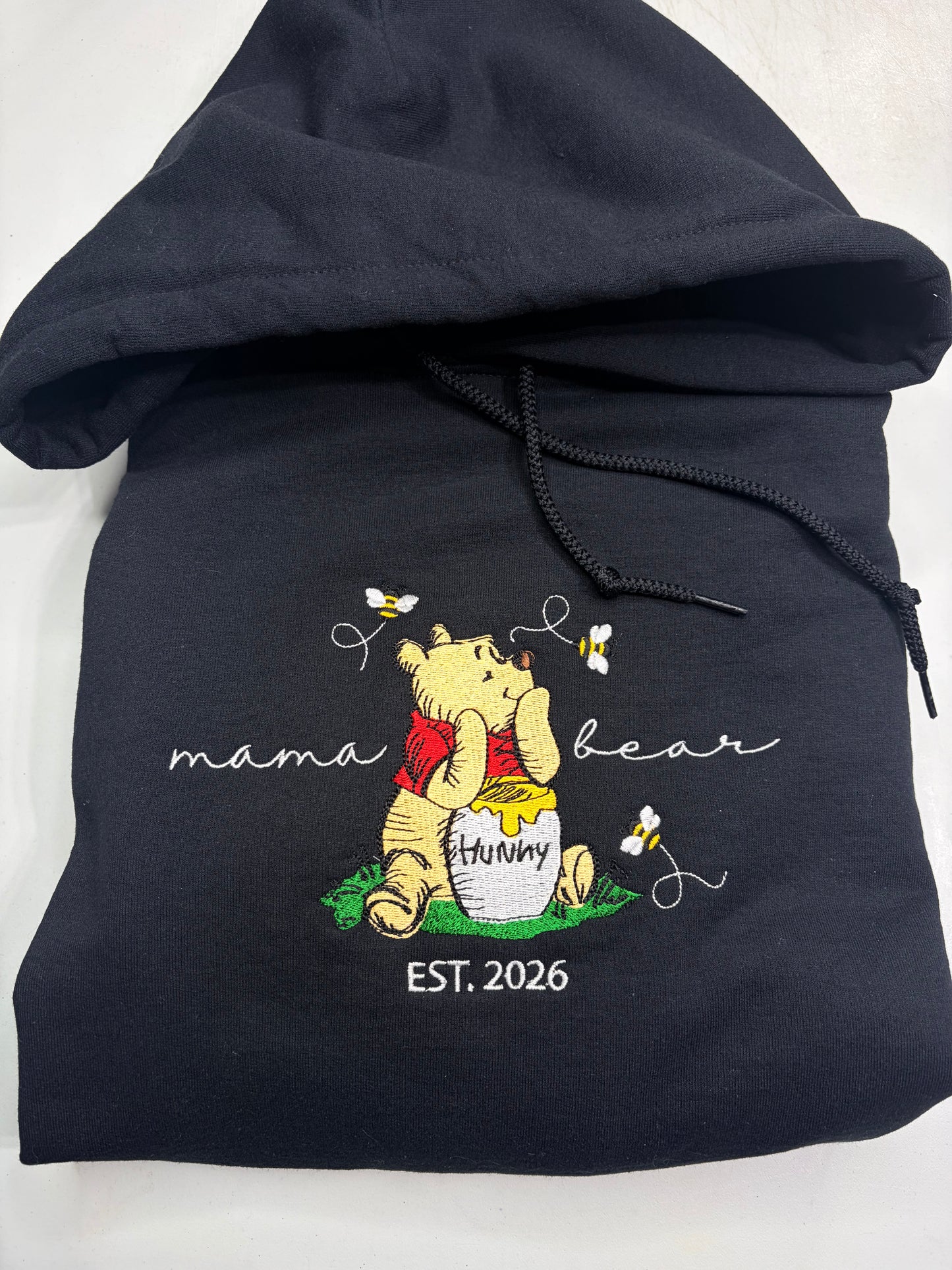black hoodie with winnie the pooh embroidered on it and says mama bear