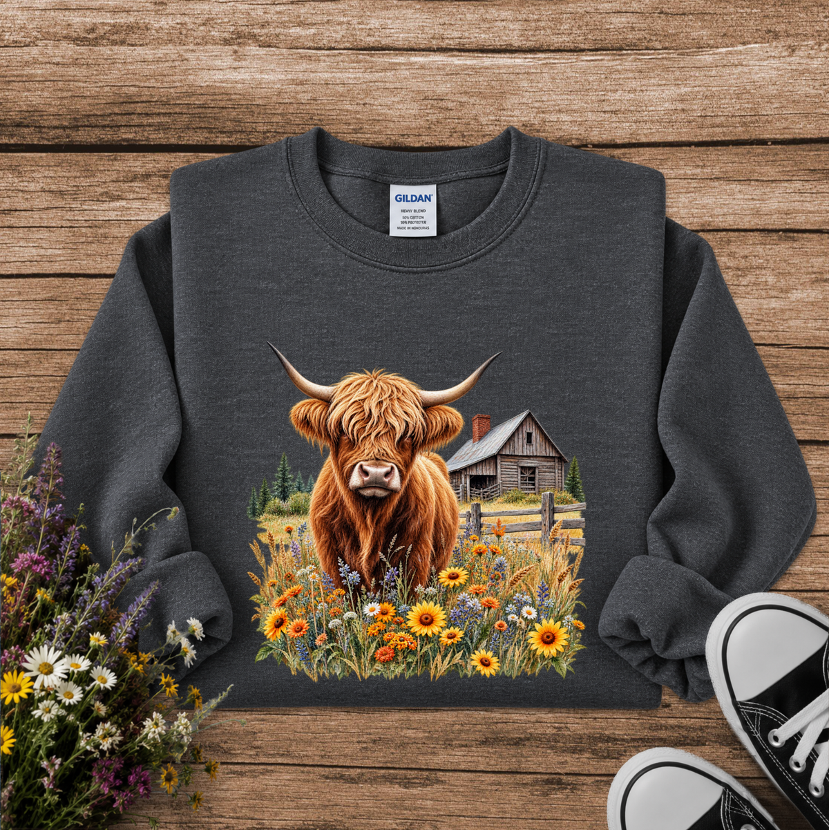 gray sweatshirt with a graphic of a highland cow standing in a field of wildflowers in front of a barn
