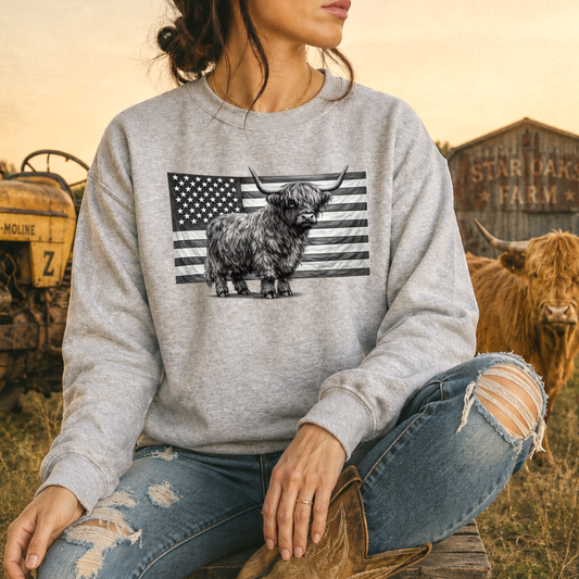 woman wearing a gray sweatshirt with highland cow standing in front of USA flag graphic design