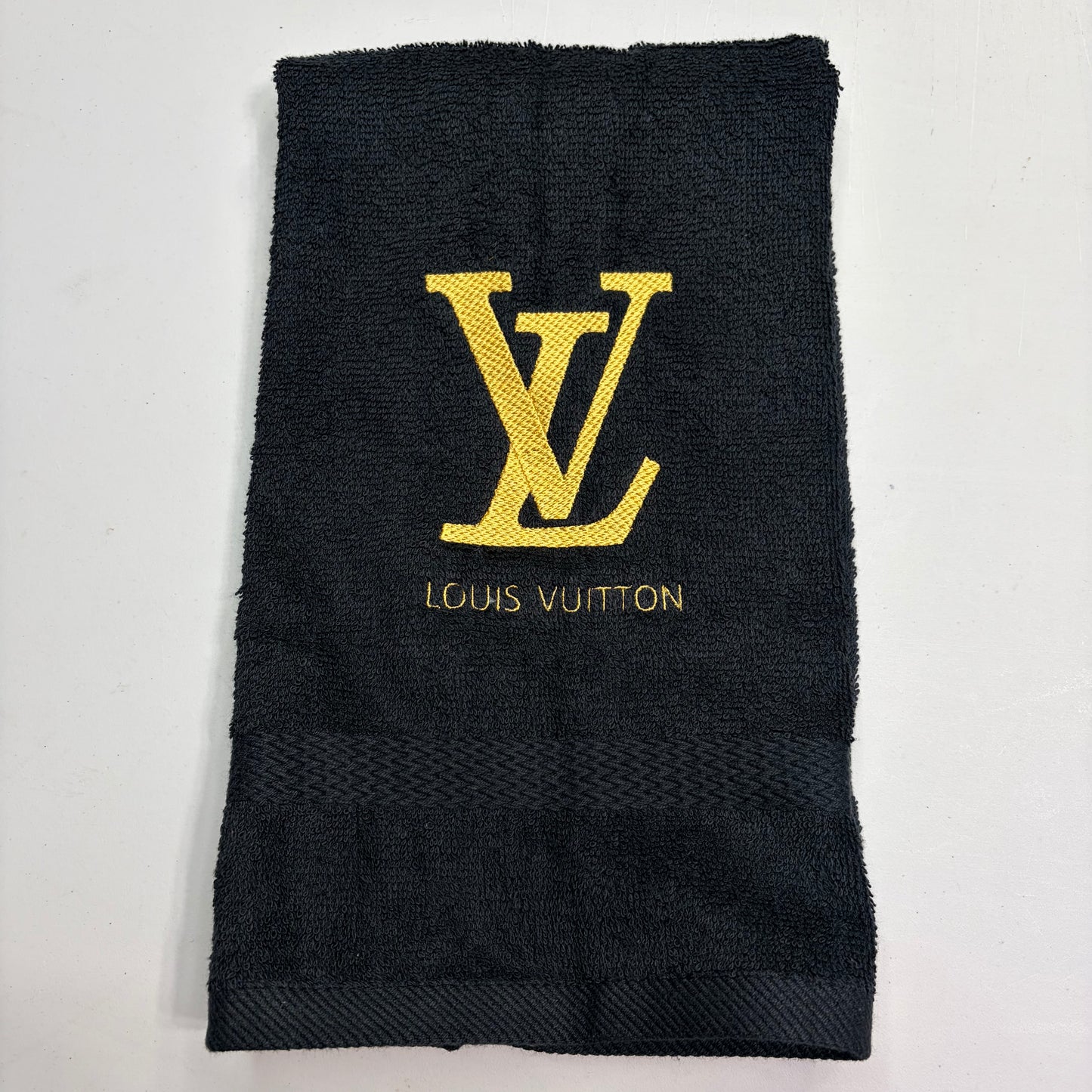 Black towel with gold Louis Vuitton logo on a white background