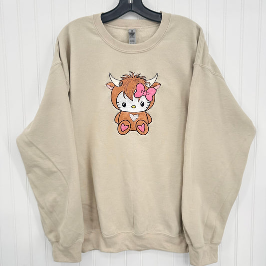 Beige sweatshirt with a cartoon highland cow design on a white background