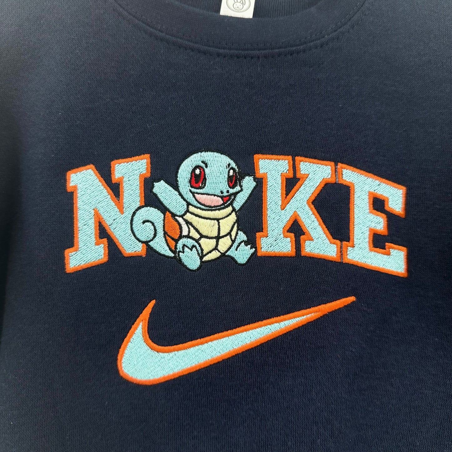 pokemon squirtle with nike logo embroidered on a navy sweatshirt