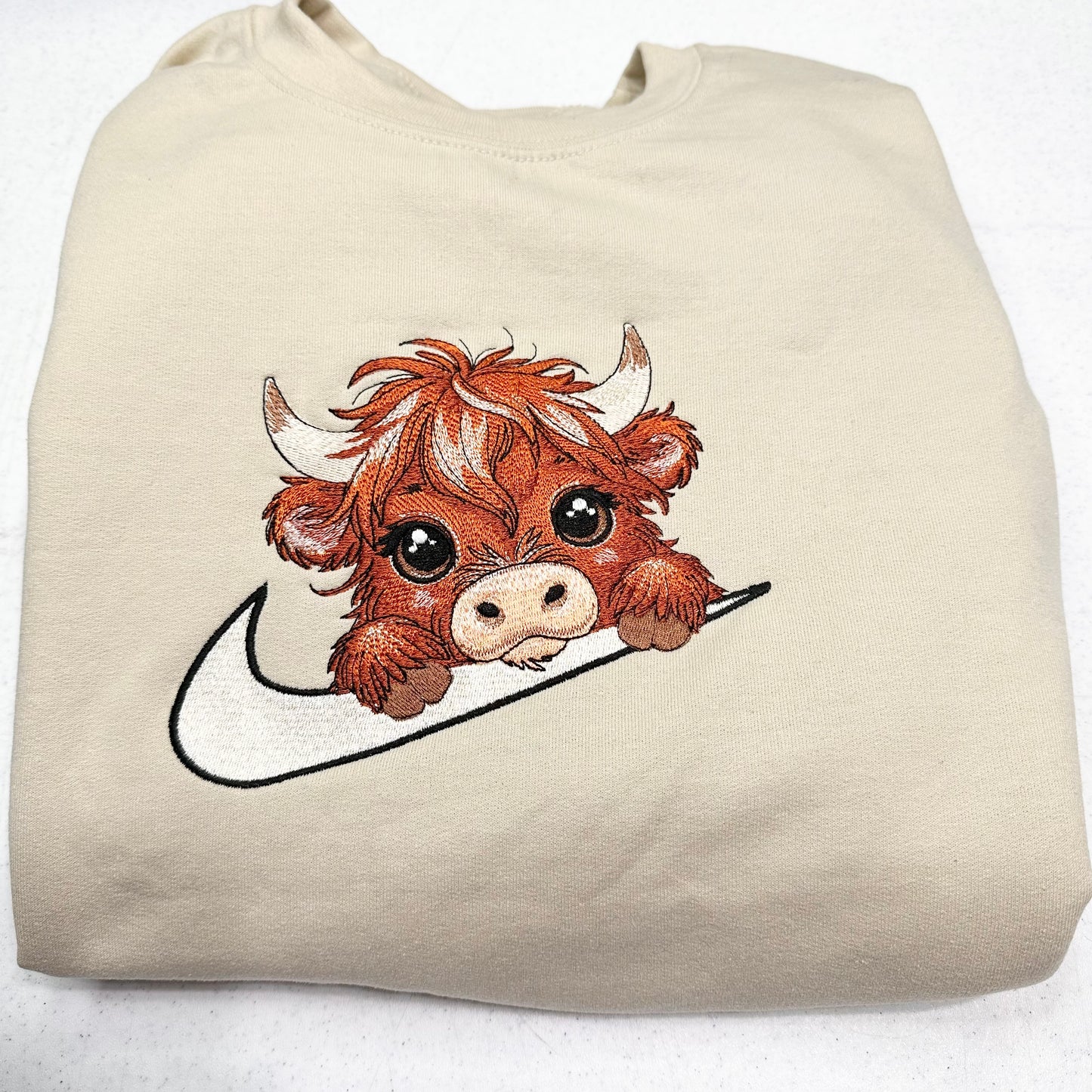 highland cow on nike swoosh on beige sweatshirt