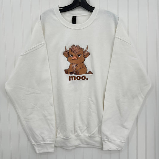 A white crewneck sweatshirt hanging on a black hanger against a white paneled wall, featuring a cartoon illustration of a brown Scottish Highland cow with the word 'moo.' printed below it.