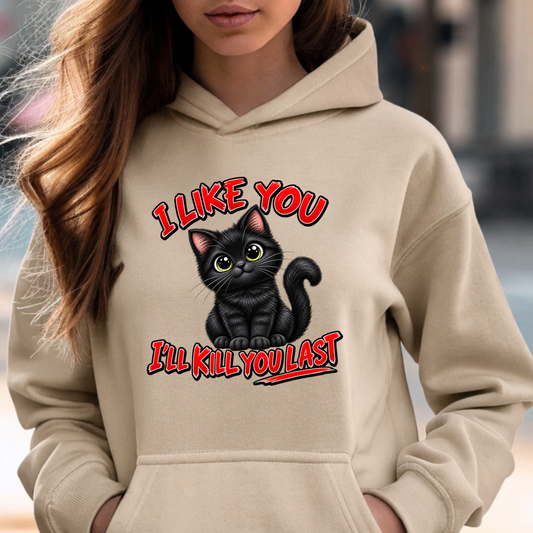 A woman wearing a beige hoodie with a graphic of a black cat and the text 'I LIKE YOU I'LL KILL YOU LAST' in red and black.
