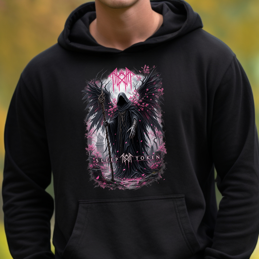 A person wearing a black pullover hoodie with a large front graphic of a dark hooded figure with wings, pink petals, and the text 'AUSTEN' and 'SLEEP TOKEN'. The background is a blurred outdoor scene in yellow-green tones.