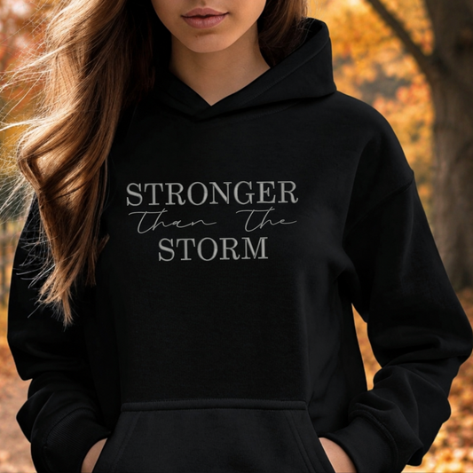 black sweatshirt with the text Stronger Than The Storm embroidered on it