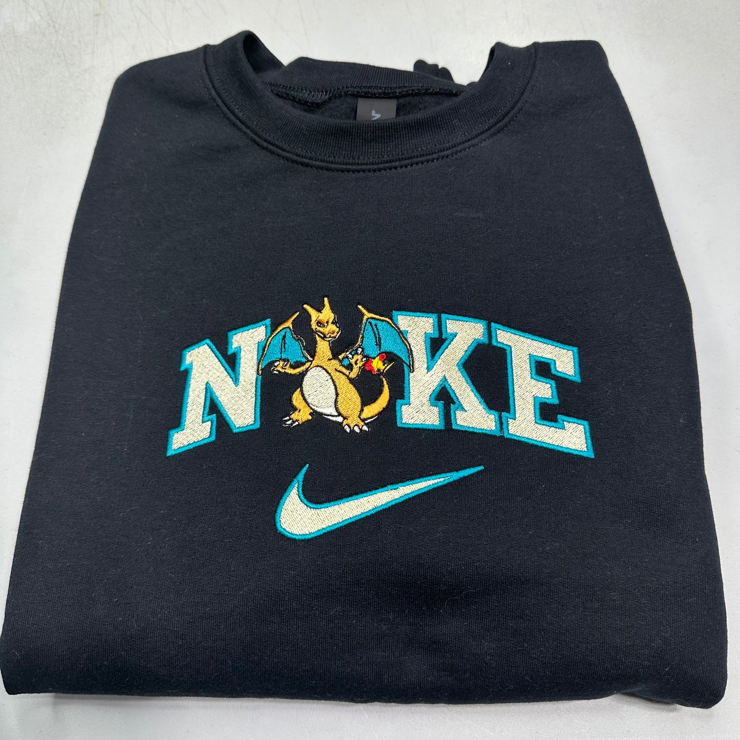 Folded black sweatshirt with a dragon graphic and 'N'ike' text on a light gray background