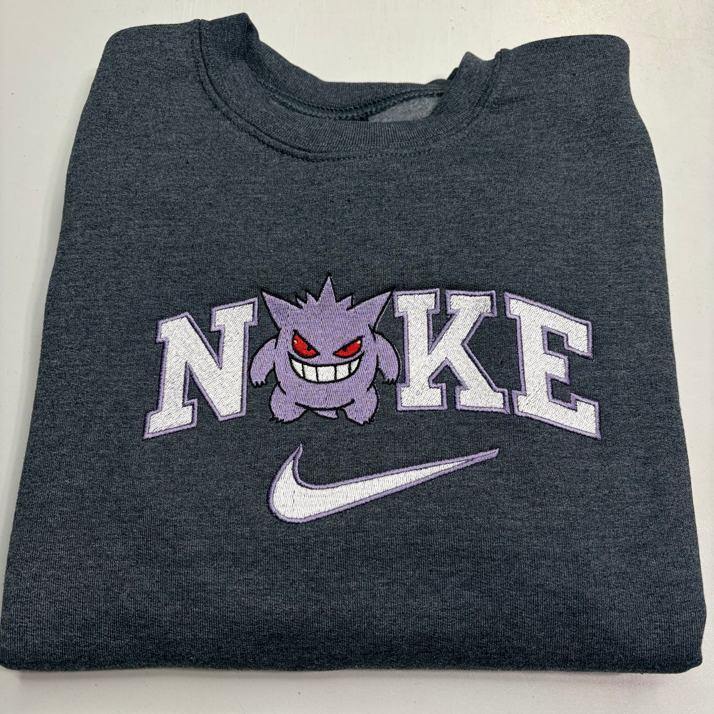 gray sweatshirt with pokemon gengar embroidered design in the nike logo on it