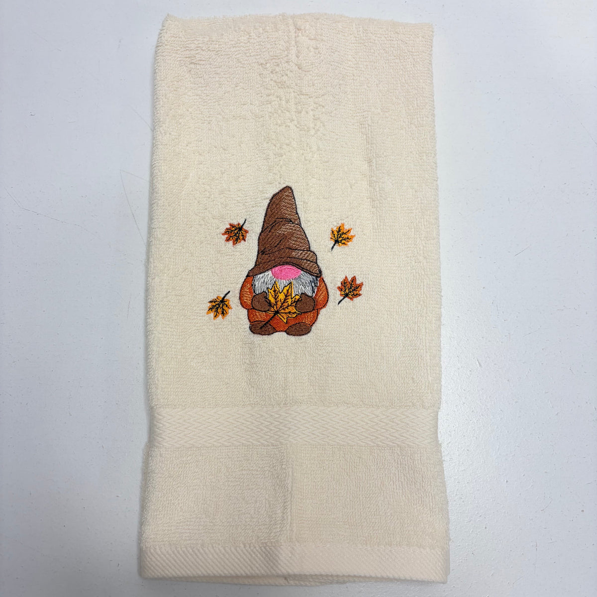 beige towel with an embroidered fall gnome design on it