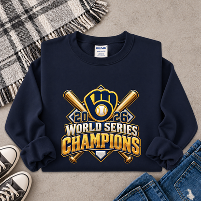 A navy blue crewneck sweatshirt with a '2026 World Series Champions' baseball graphic, styled in a flat lay with a plaid blanket, sneakers, and jeans on a gray concrete background.