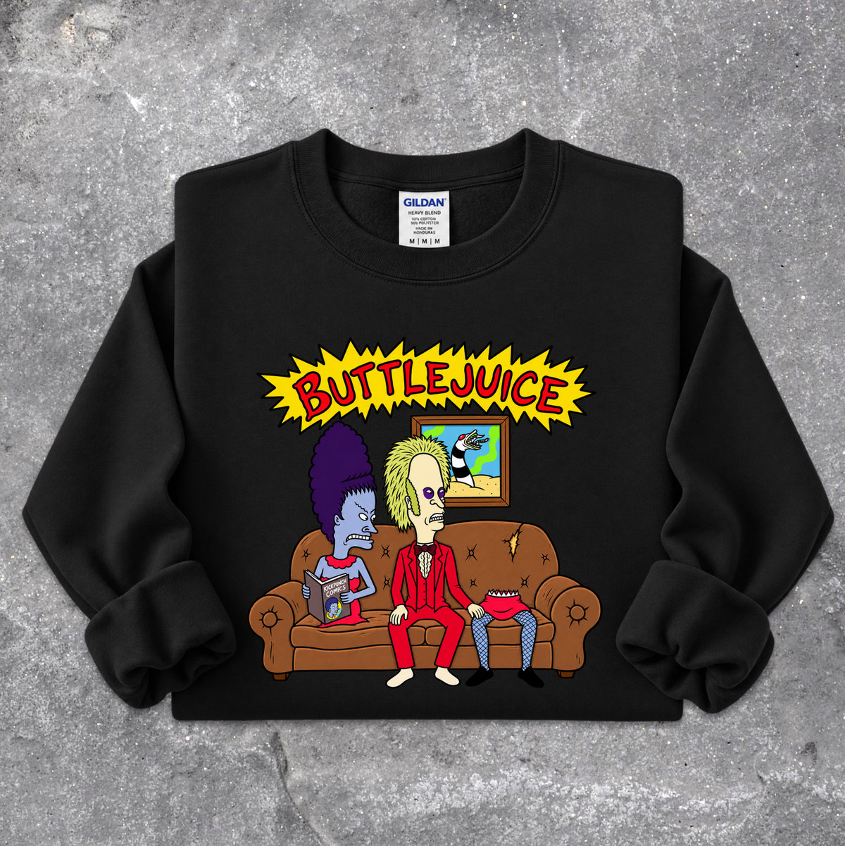 A black crewneck sweatshirt featuring a colorful cartoon graphic of two characters sitting on a brown couch under a yellow 'BUTTLEJUICE' text graphic, displayed flat on a gray concrete-textured background. The neck label shows the brand Gildan.