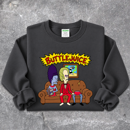 A black Gildan sweatshirt featuring a colorful graphic print of two cartoon characters sitting on a brown couch under a yellow 'BUTTLEJUICE' starburst, laid flat on a gray concrete-textured background.