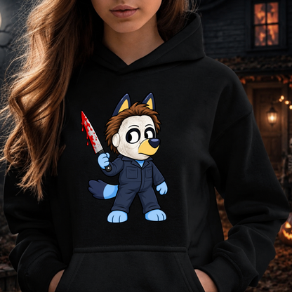 A woman wearing a black hoodie with a cartoon graphic of a bluey character in a blue jumpsuit holding a blood-splattered knife, shown against a dark outdoor background.