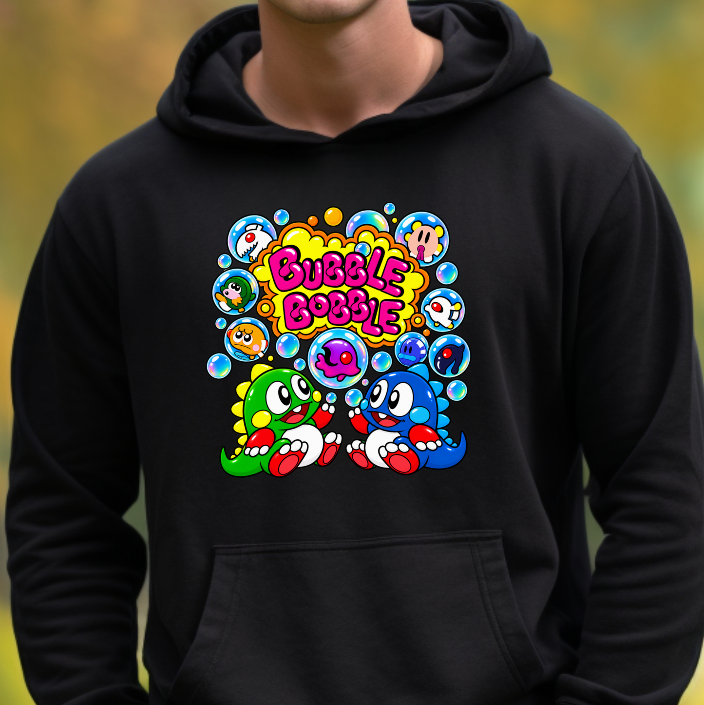 A person wearing a black pullover hoodie with a colorful cartoon graphic on the chest. The graphic features the text 'Bubble Bobble' in pink and yellow, surrounded by blue bubbles and two cartoon characters, one green and one blue, with red accents.