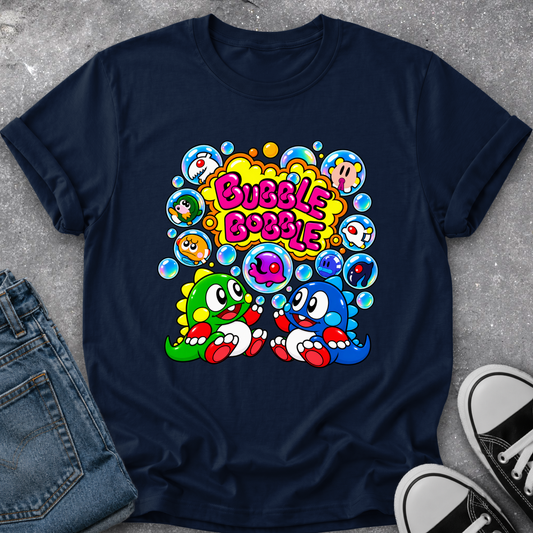 A navy blue short-sleeve t-shirt with a colorful retro cartoon graphic on the chest. The graphic features the text 'Bubble Bobble' in pink bubble letters, surrounded by colorful bubbles and two cartoon characters, one green and one blue.
