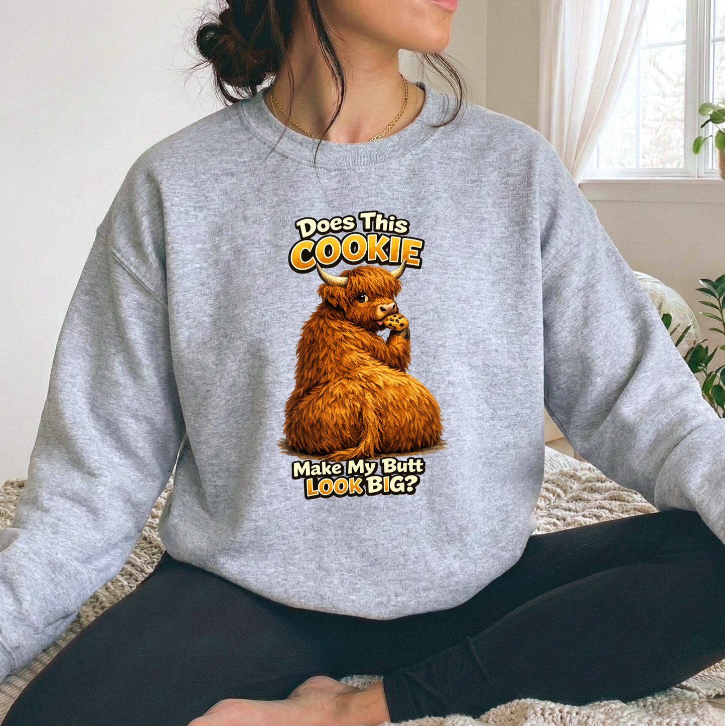 woman wearing a gray sweatshirt with funny highland cow graphic design that says does this cookie make my butt look big