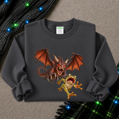 A dark gray crewneck sweatshirt featuring a graphic print of a red dragon and a green frog, styled flat on a textured gray background with holiday lights and plaid fabric accents.