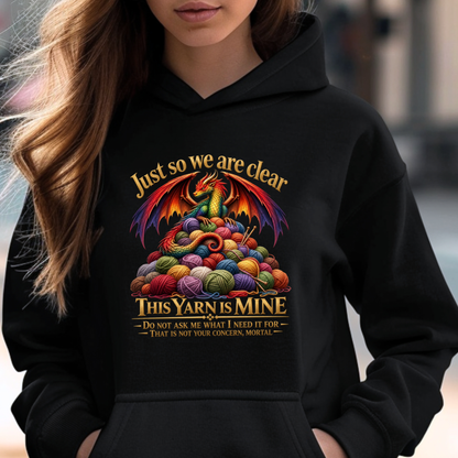A woman wearing a black hoodie with a colorful graphic of a dragon surrounded by balls of yarn and the text 'Just so we are clear THIS YARN IS MINE'.
