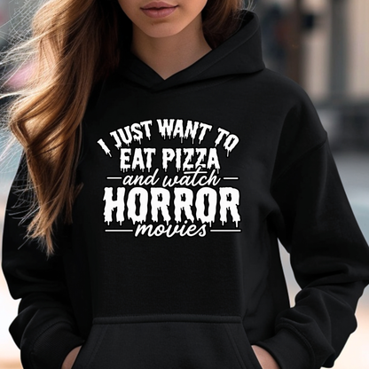 A woman wearing a black hoodie with a white graphic text print that reads 'I JUST WANT TO EAT PIZZA and watch HORROR movies'.