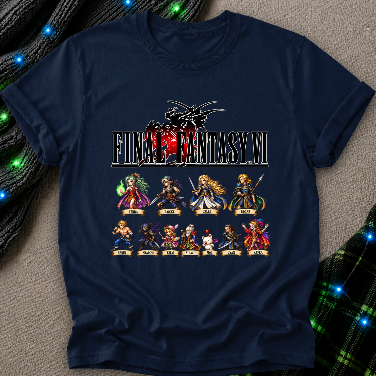 A navy blue graphic t-shirt featuring the Final Fantasy VI logo and character lineup print, laid flat on a textured gray surface with decorative green and black plaid fabric and blue string lights in the corners.