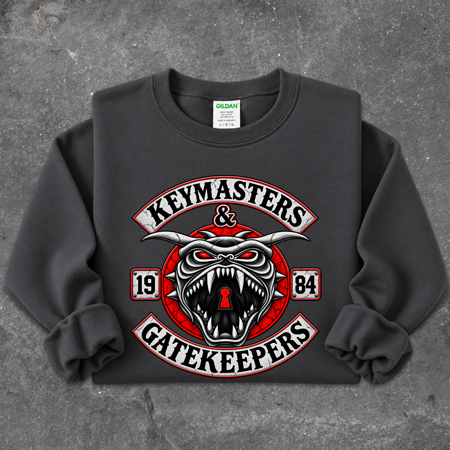 A dark gray crewneck sweatshirt featuring a large graphic print of a snarling horned devil with the words 'KEYMASTERS & GATEKEEPERS' and '1984' on a textured gray background.
