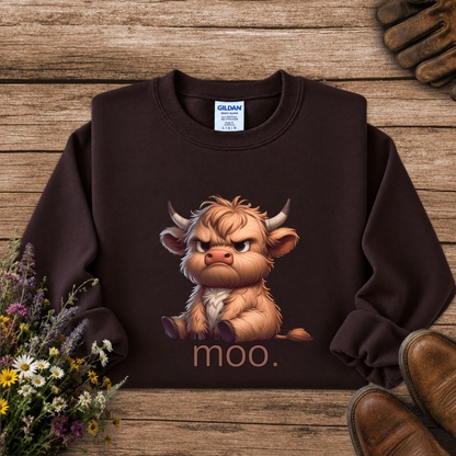 A dark brown crewneck sweatshirt featuring a graphic of a fluffy, angry Highland cow with the word 'moo.' underneath, displayed in a flat-lay arrangement on a rustic wooden background with gloves, flowers, and boots.