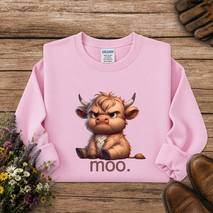 A pink long-sleeve sweatshirt laid flat on a rustic wooden surface, featuring a cartoon Highland cow graphic with the word 'moo.' underneath.