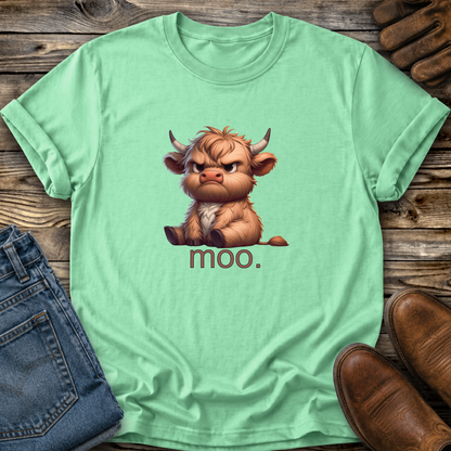Light green t-shirt with a cartoon cow and 'moo.' text on a wooden surface with jeans and shoes.