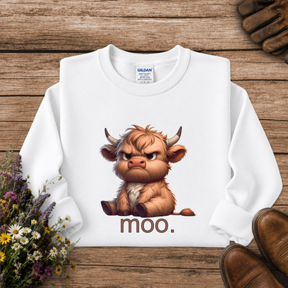 A white long-sleeve sweatshirt laid flat on a rustic wooden surface, featuring a cartoon illustration of an angry brown Highland cow with the word 'moo.' printed below.