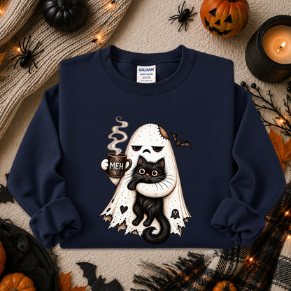 A navy blue crewneck sweatshirt featuring a cartoon graphic of a white ghost with a skull face holding a black cat and a mug that says 'MEH'. The sweatshirt is displayed in a flat-lay arrangement with Halloween props including a pumpkin, spider decorations, a candle, and a knitted sweater.