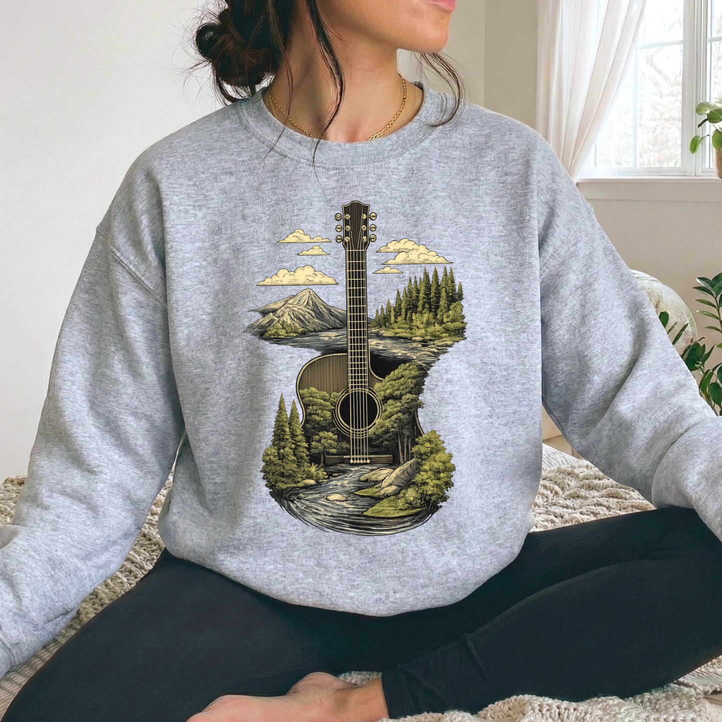 woman wearing a gray swearshirt with a guitar and country mountains and forest scenery graphic design