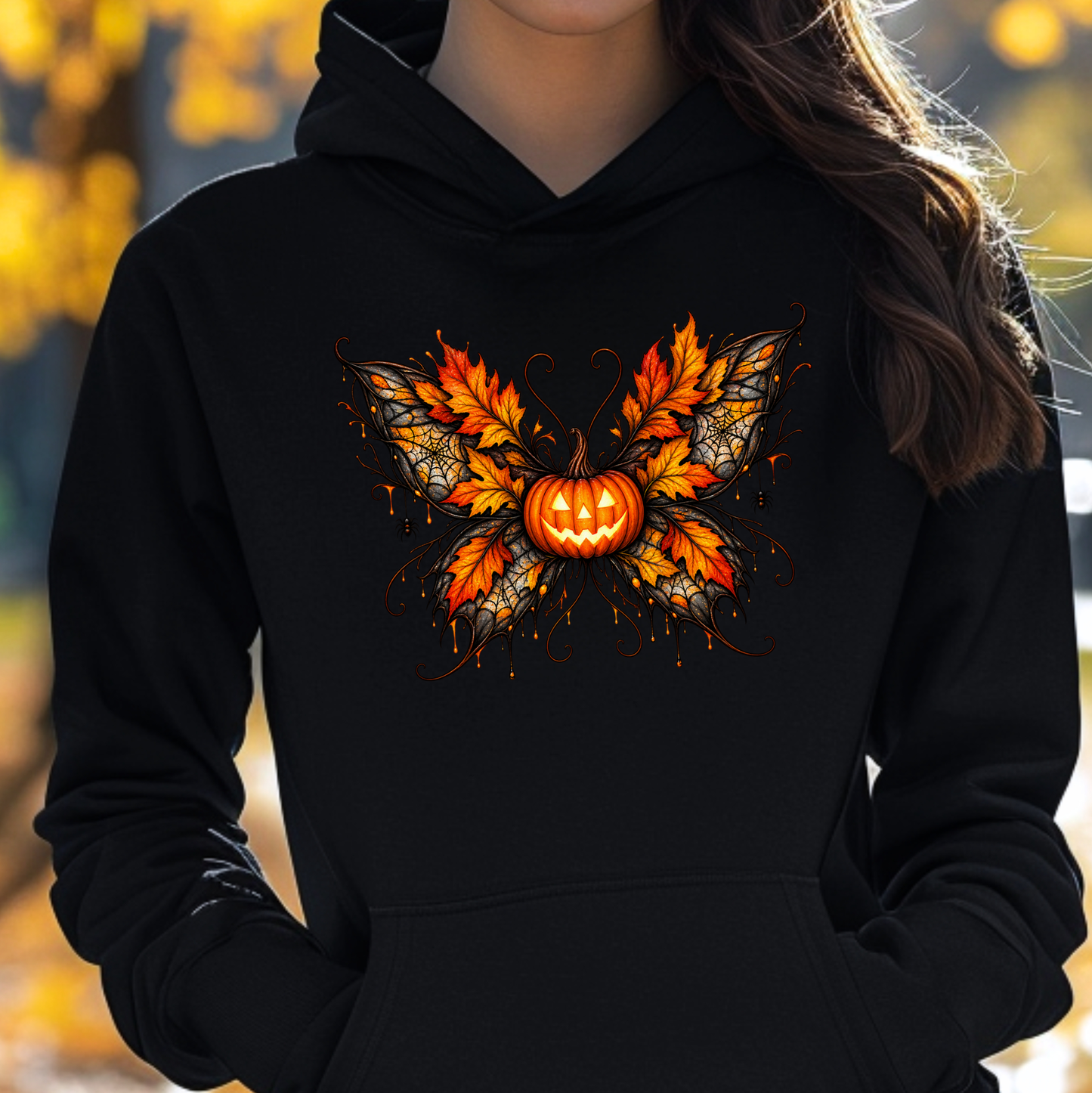 woman wearing a black hooded sweatshirt with a fall autumn halloween pumpkin theme graphic on it