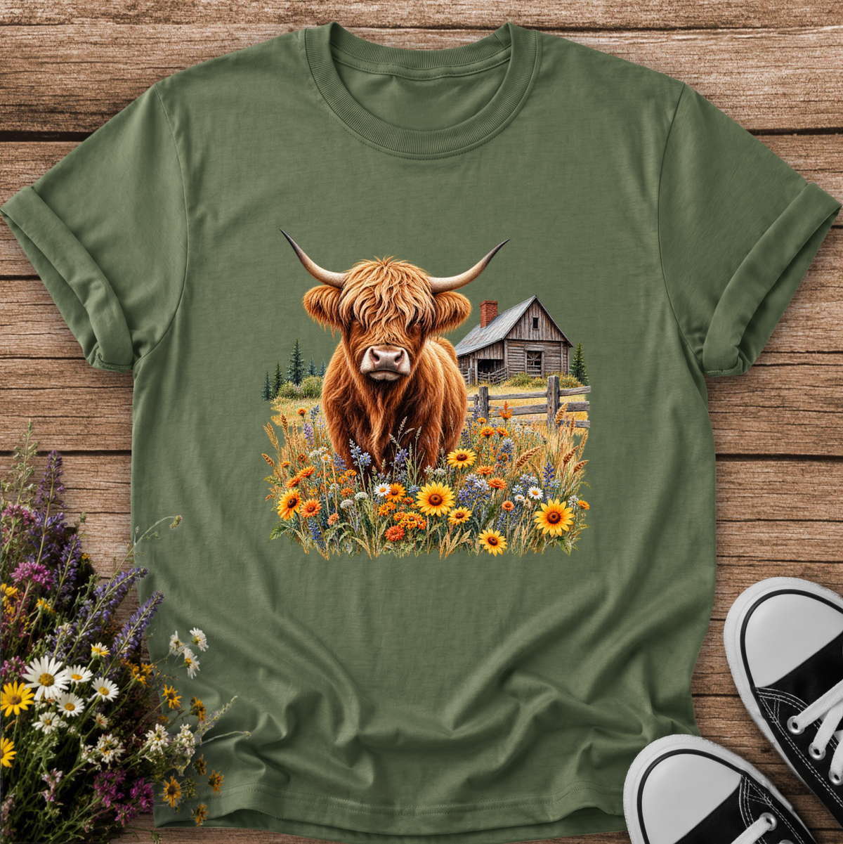 green tshirt with a graphic of a highland cow standing in a field of wildflowers in front of a barn