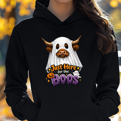 woman wearing a black sweatshirt with a highland cow wearing a halloween ghost costume and says just here for the boos