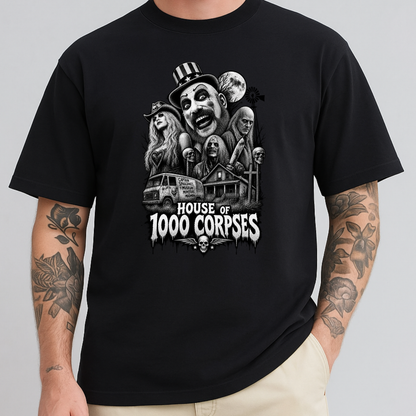 A man wearing a black short-sleeve graphic t-shirt with a detailed black and white horror illustration of the 'House of 1000 Corpses' on the chest, paired with beige pants, against a solid gray background.