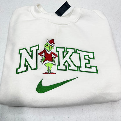 White sweatshirt with a grinch design and 'Nike' logo on a light gray background