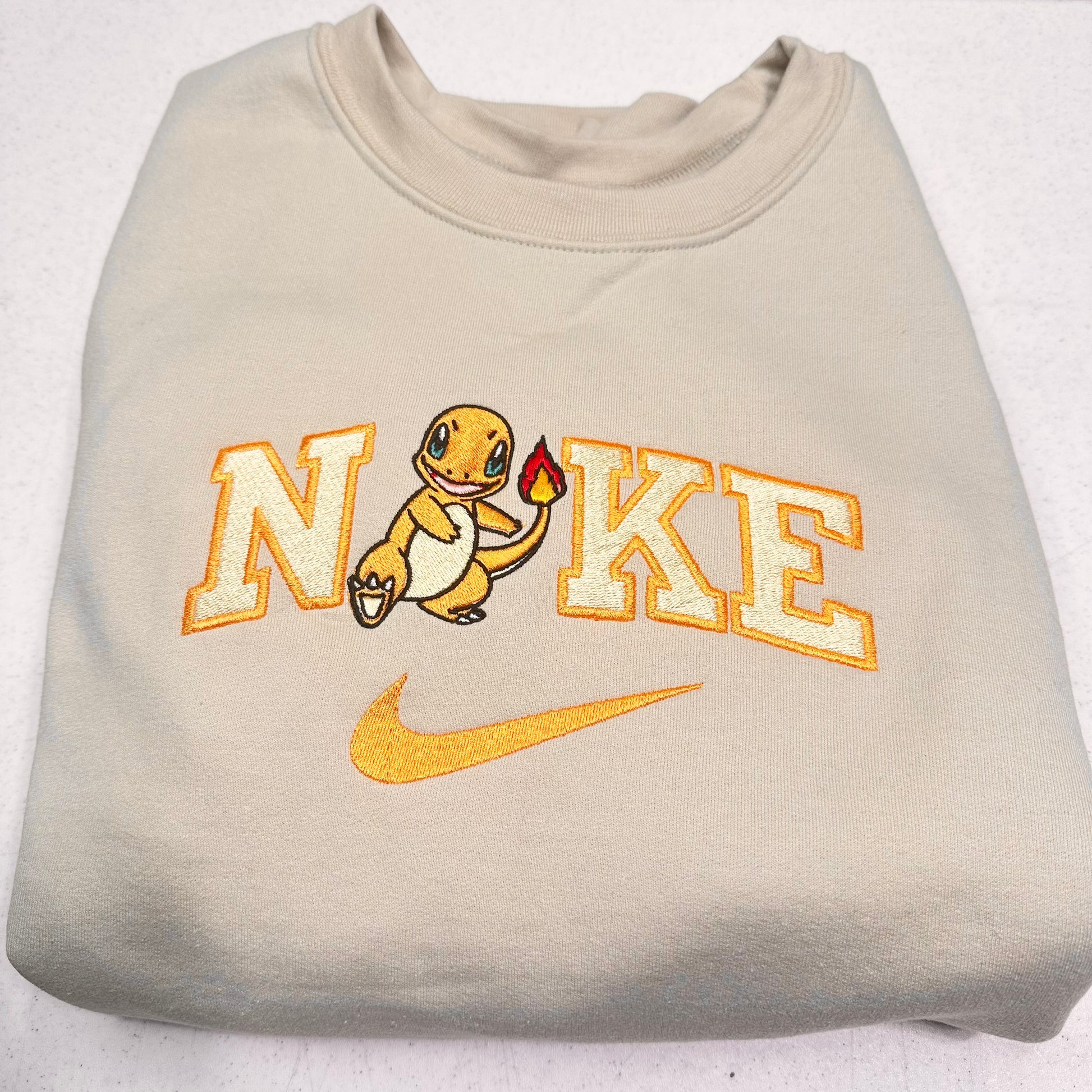 beige sweatshirt with pokemon charmander and the nike logo on it