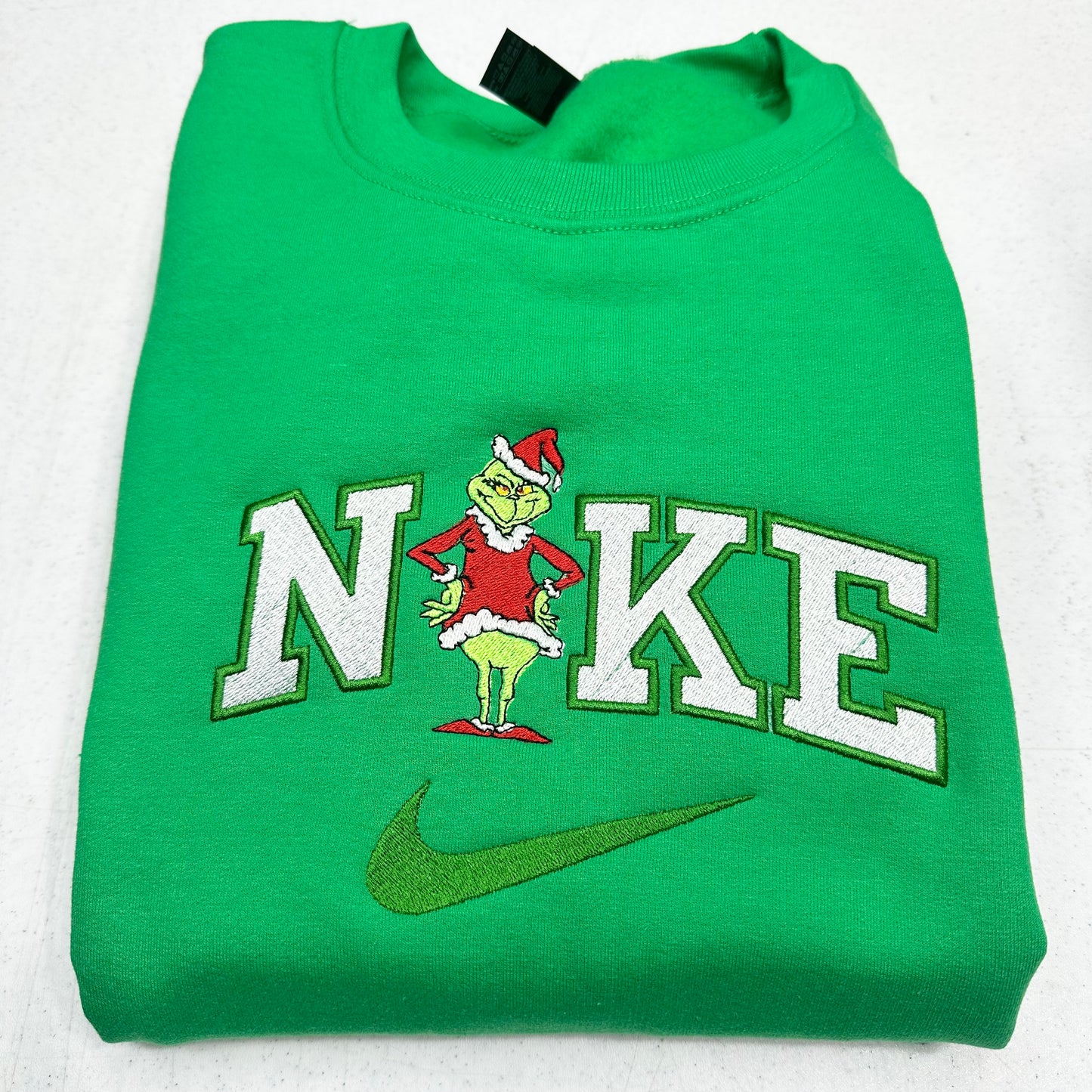 Green sweatshirt with a grinch design and 'Nike' logo on a white background