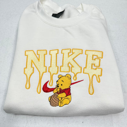white sweatshirt with embroidered winnie the pooh with honey dripping from the nike logo