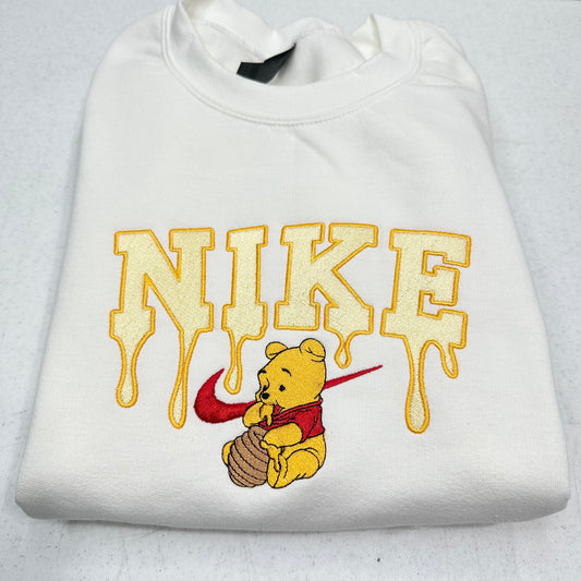 white sweatshirt with embroidered winnie the pooh with honey dripping from the nike logo