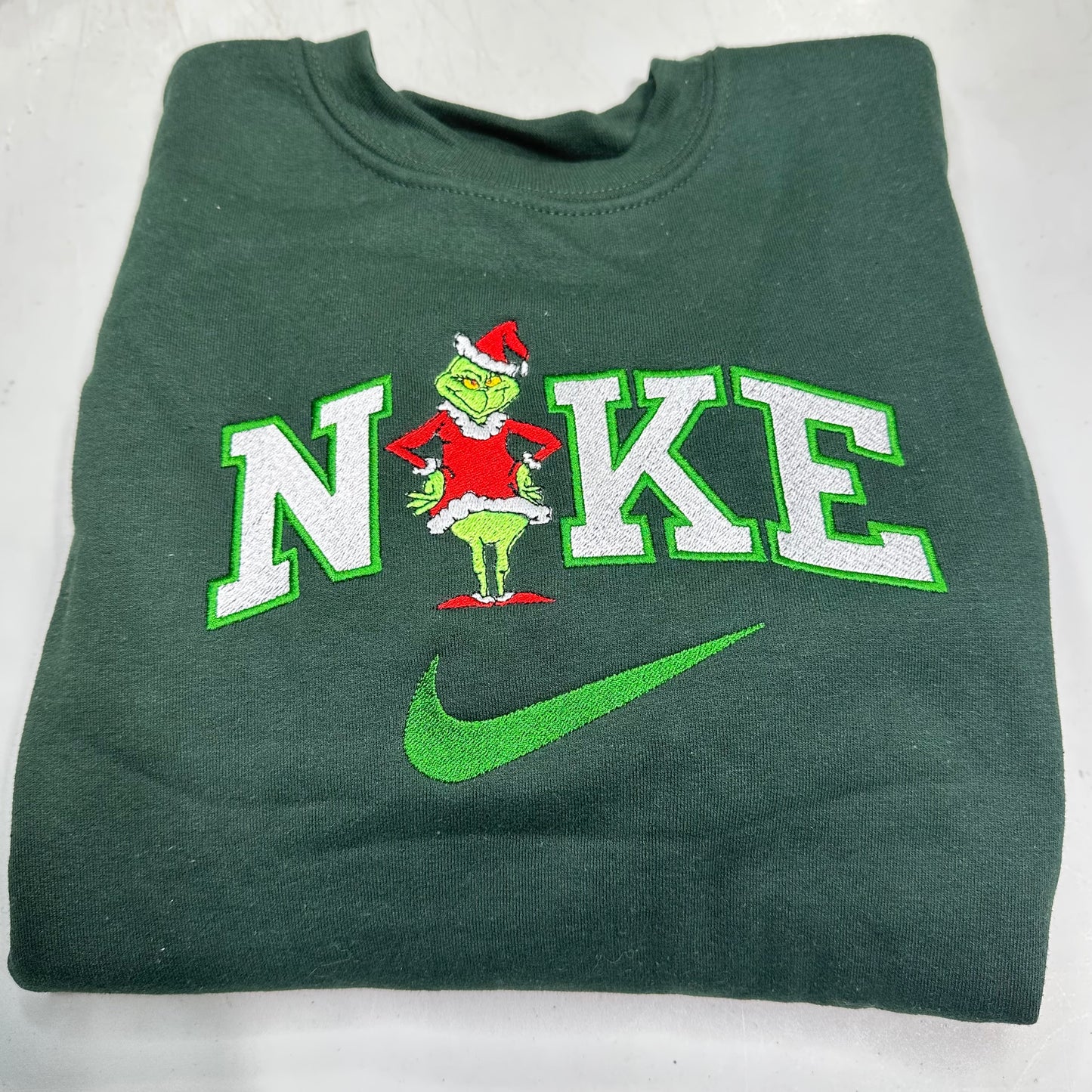 Green sweatshirt with a grinch design and 'Nike' text on a white background
