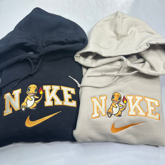 Two hoodies, one black and one beige, with a cartoon pokemon charmander character and 'Nike' branding on a white background.