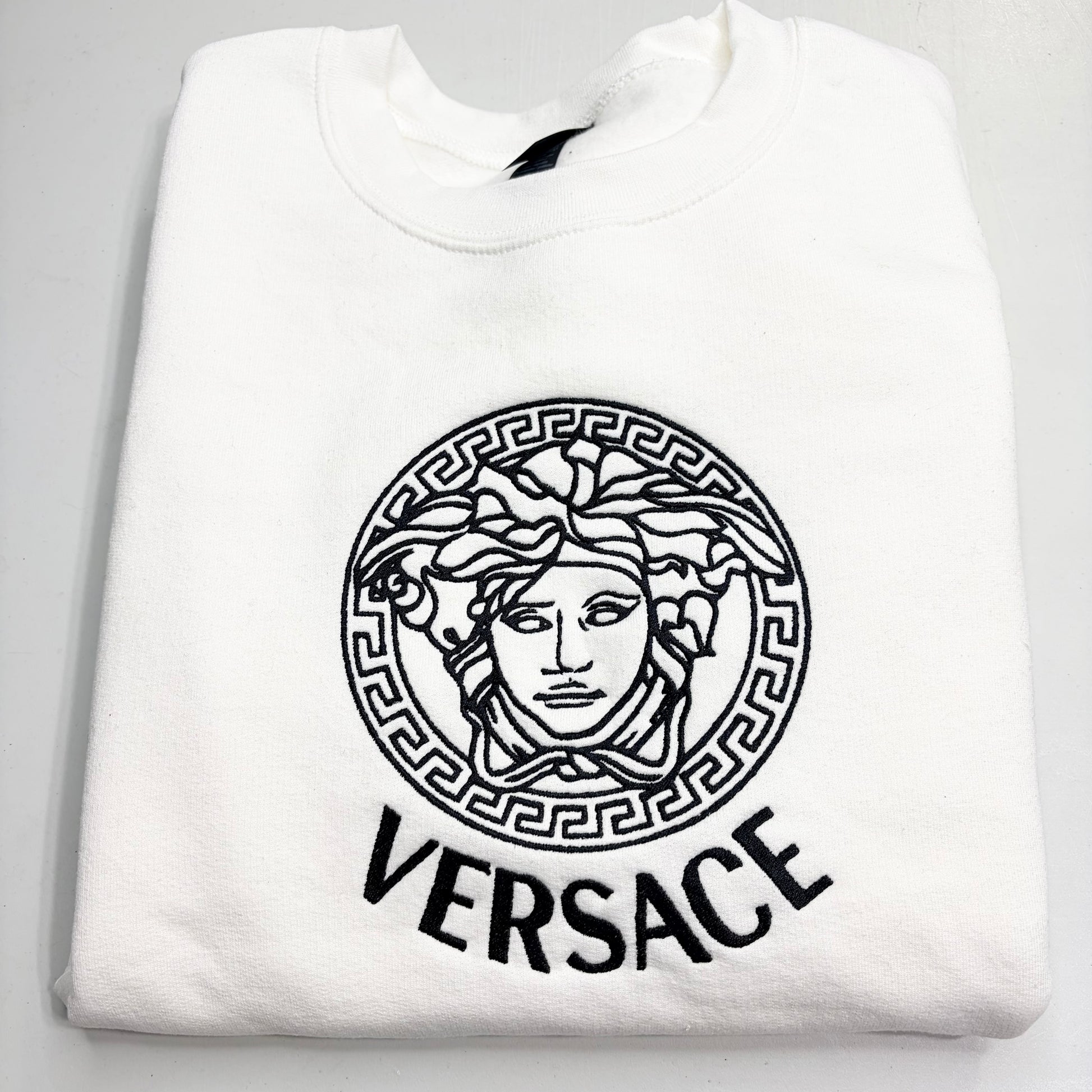 White sweatshirt with versace logo on a light gray background