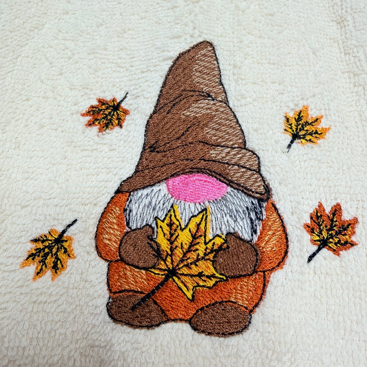 beige towel with an embroidered fall gnome design on it
