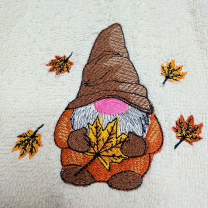 beige towel with an embroidered fall gnome design on it