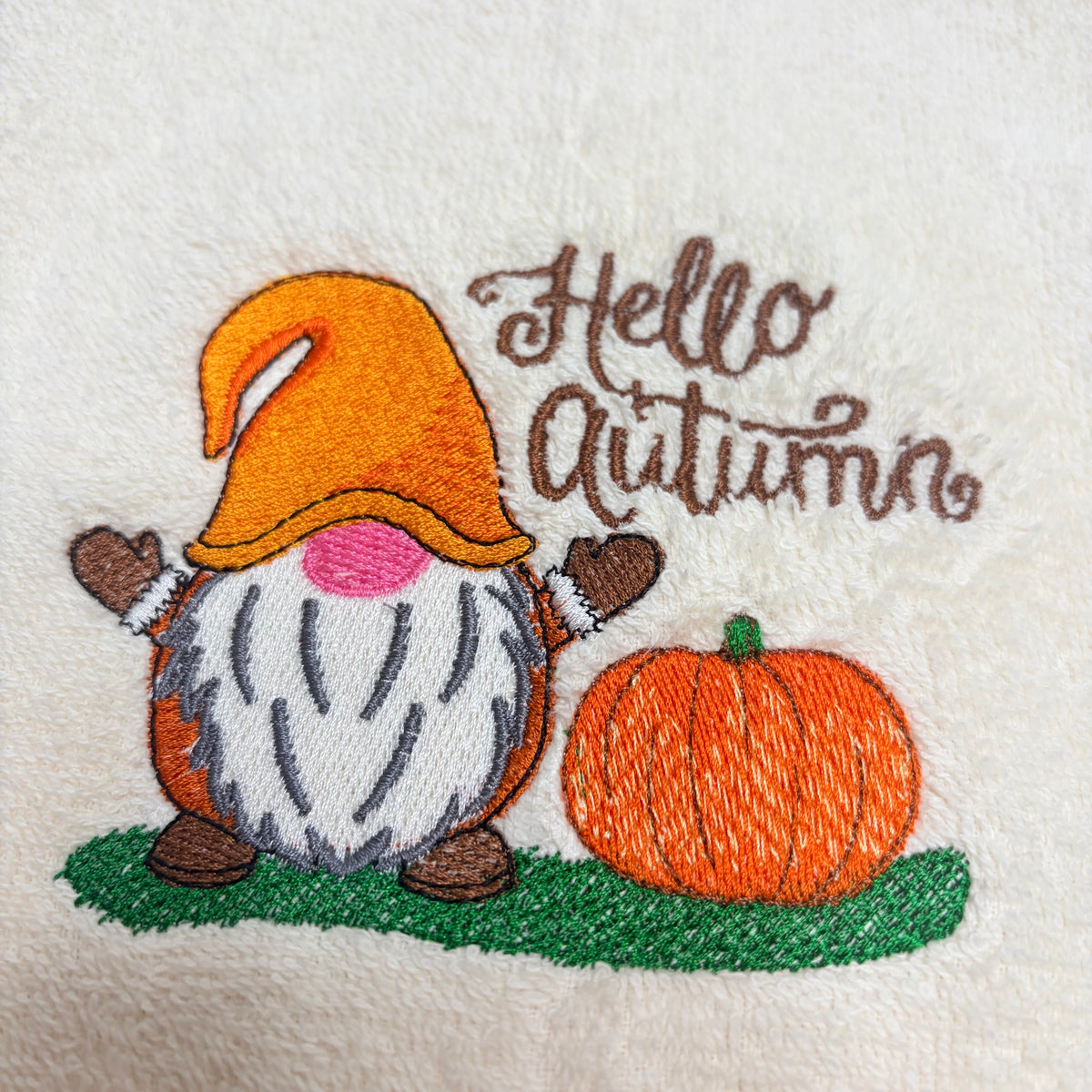 beige towel with an embroidered fall gnome design on it
