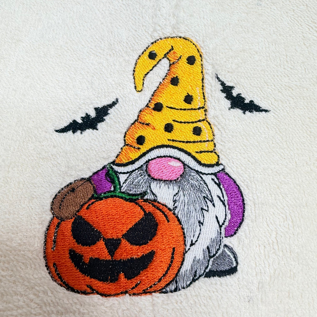 beige towel with an embroidered fall halloween gnome design on it
