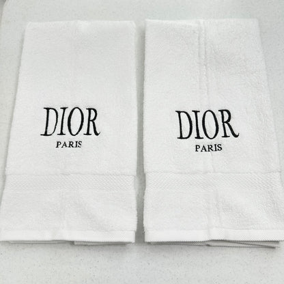Two white Dior towels with black text on a light gray background
