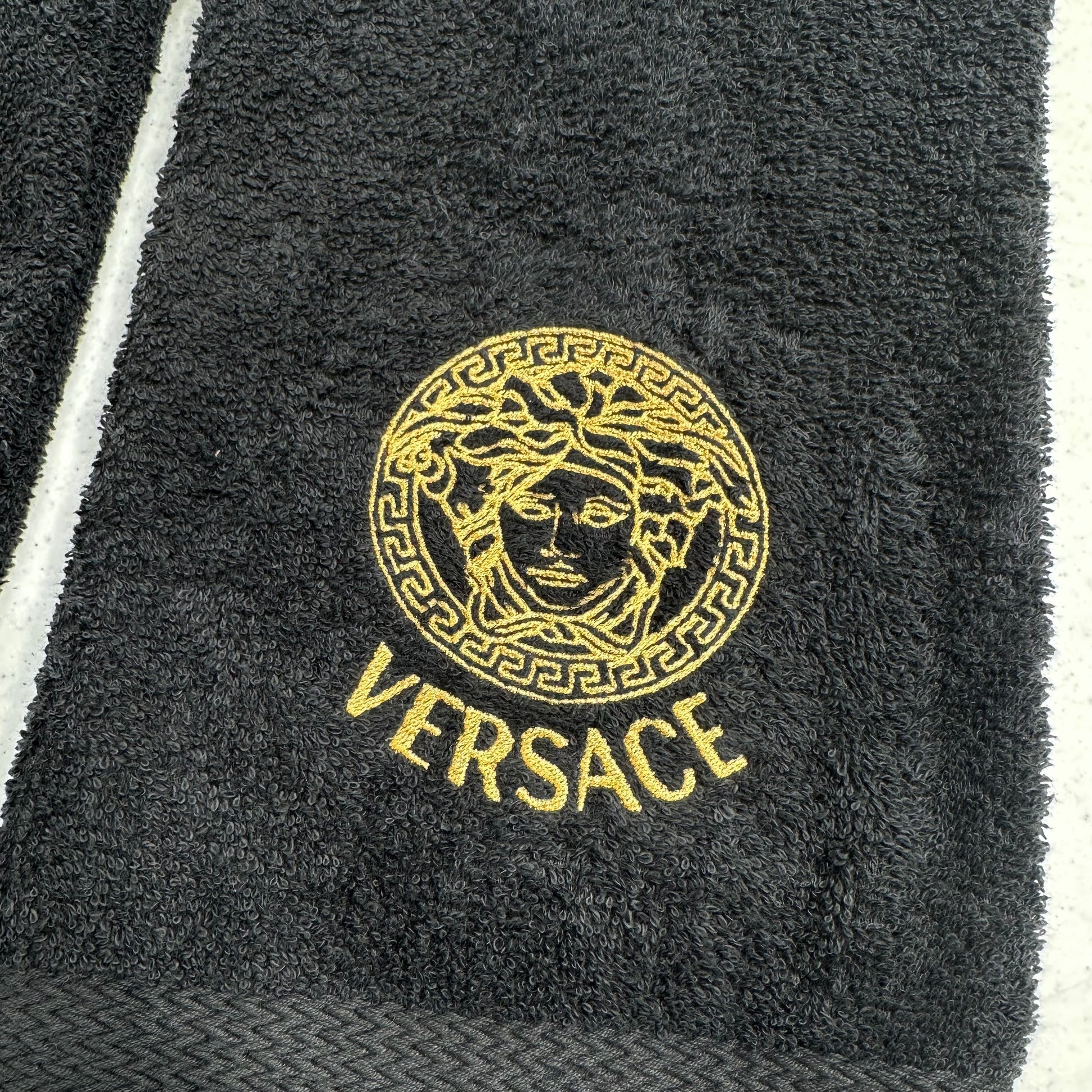 Black towel with Versace logo on a white background